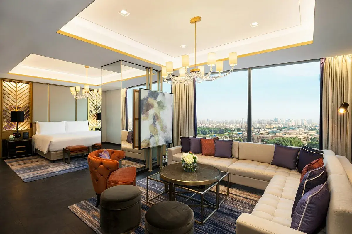 A Waldorf Astoria Kuwait suite with a lounge, crystal chandeliers and floor-to-ceiling windows over the city